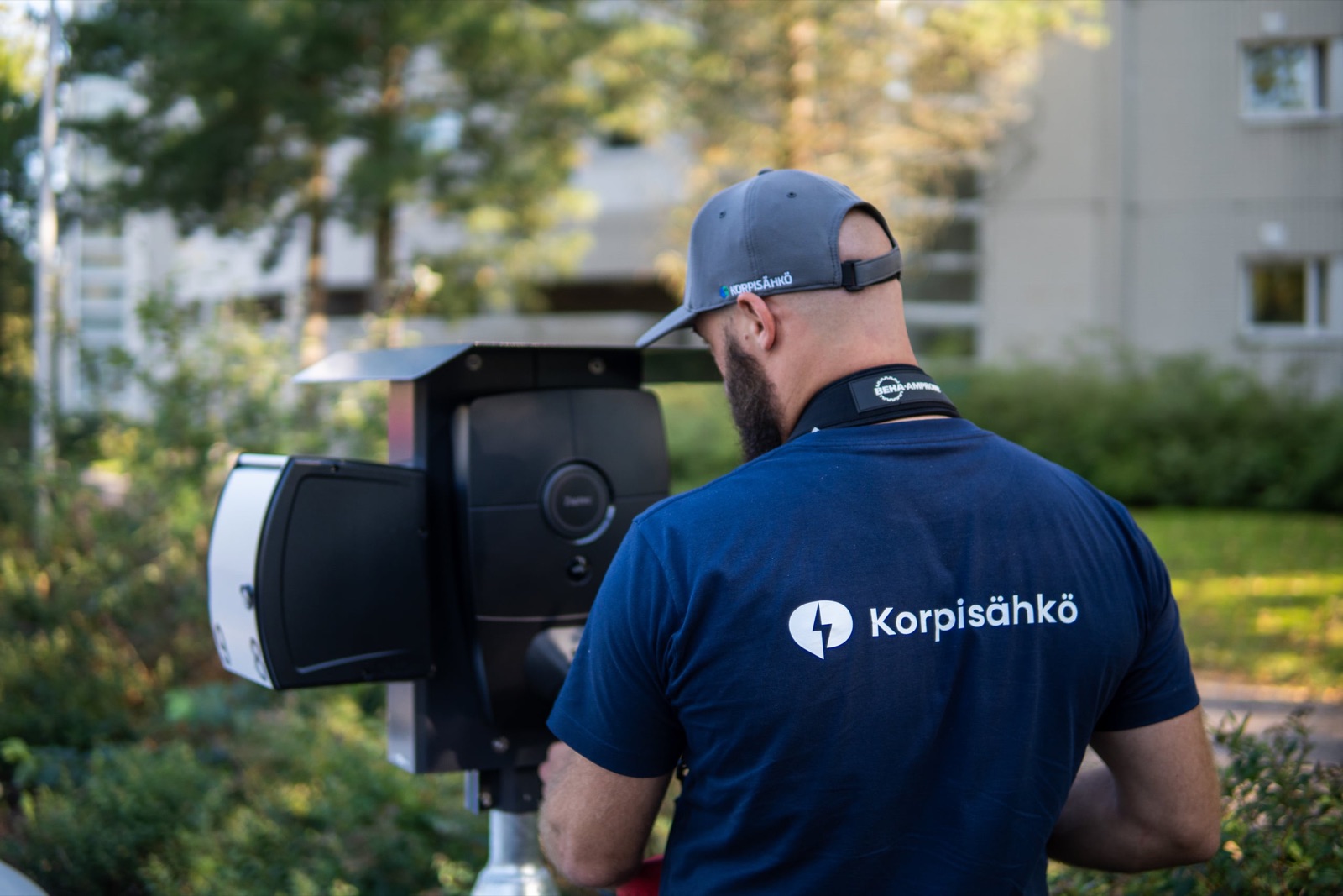 Korpisähkön asentaja asentaa sähköauton latausasemaa taloyhtiön pihaan